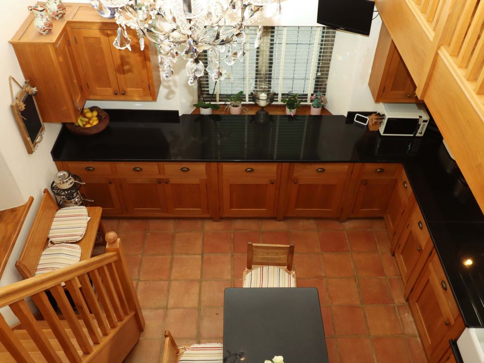 A kitchen with wooden cabinets and black countertop at Higher Wadden Farm Southleigh