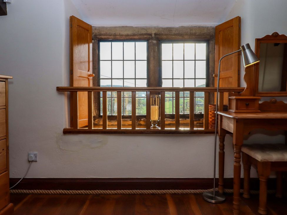 A bedroom with a window and table at Higher Wadden Farm in Southleigh