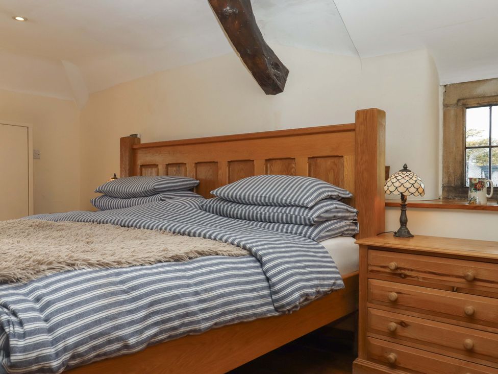 A bedroom with a wooden bed and lamp at Higher Wadden Farm Southleigh