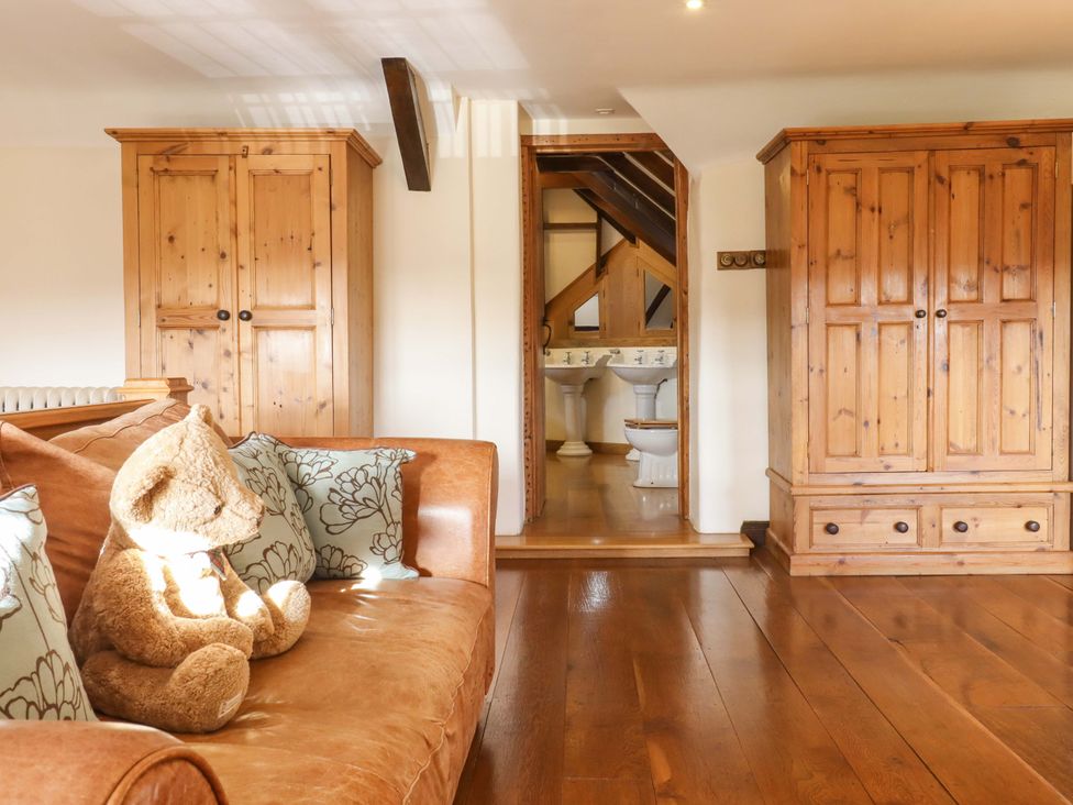 A living room with a teddy bear and wooden cabinets at Higher Wadden Farm in Southleigh