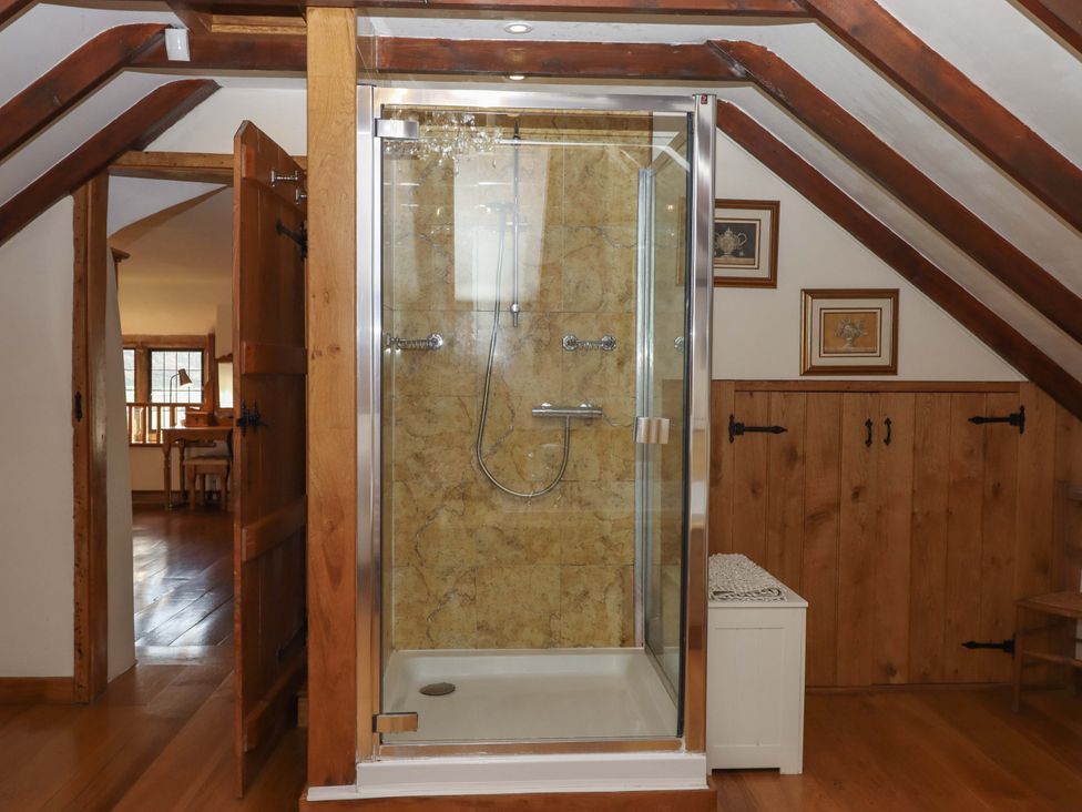 A bathroom with a shower and wooden elements at Higher Wadden Farm in Southleigh