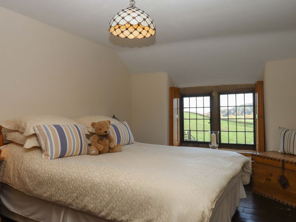 A bedroom with a bed and window at Higher Wadden Farm in Southleigh
