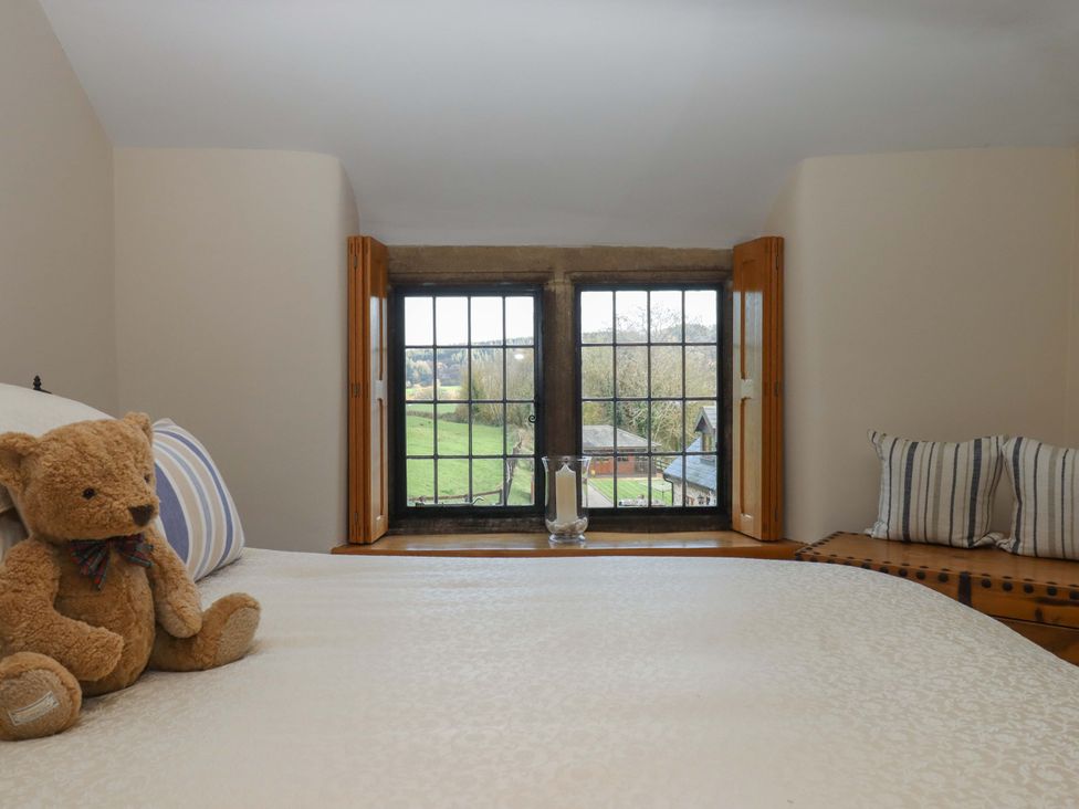 A bedroom with a teddy bear and window view at Higher Wadden Farm Southleigh