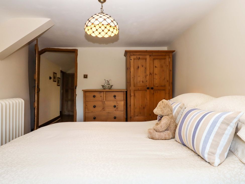 A bedroom with a bed, wardrobe, and chest of drawers at Higher Wadden Farm in Southleigh