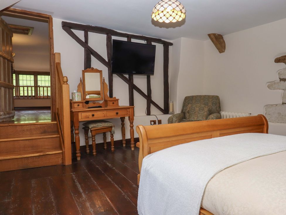 A bedroom with a bed and a mirror at Higher Wadden Farm in Southleigh