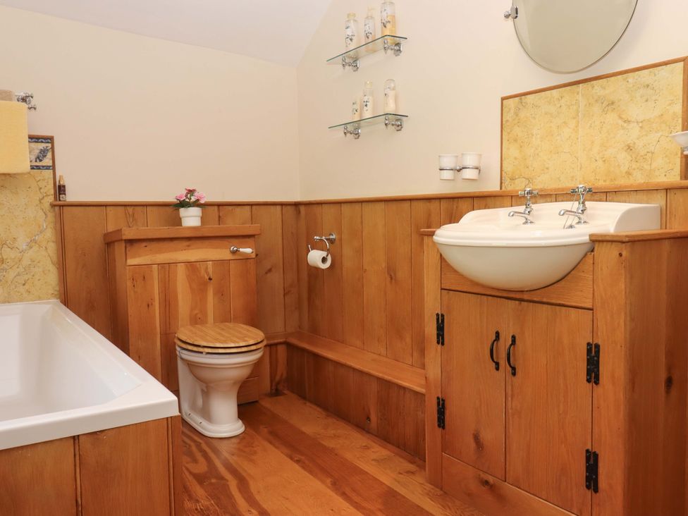 A bathroom with a bath tub, toilet, sink and storage at Higher Wadden Farm in Southleigh