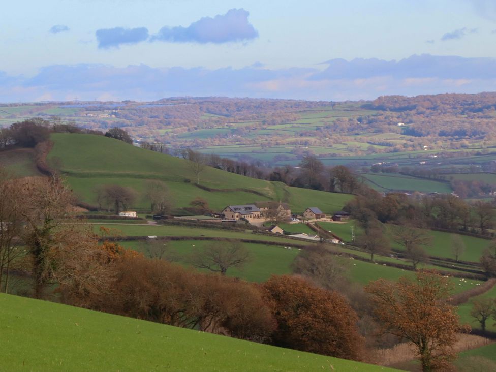A landscape view with hills and a farm at Higher Wadden Farm Southleigh