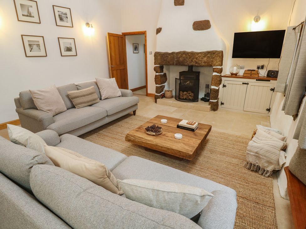 A living room with a fireplace and a coffee table at Riverside Barn in Stithians