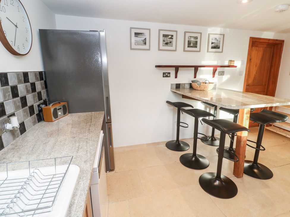 A kitchen with a refrigerator and bar stools at Riverside Barn in Stithians