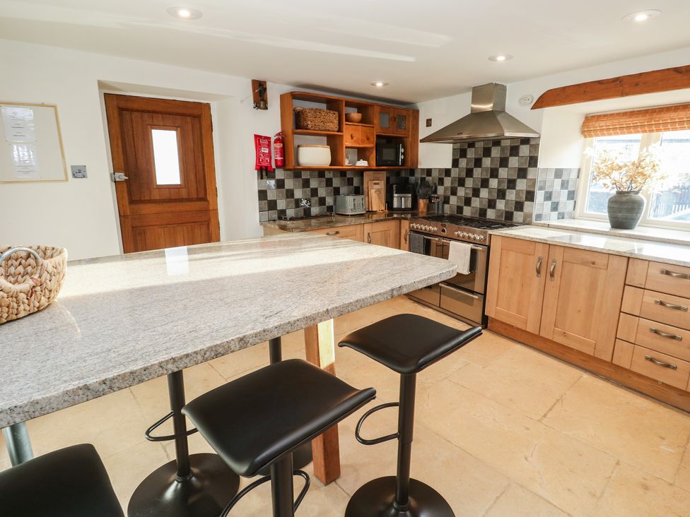 A kitchen with cabinets and bar stools at Riverside Barn Stithians