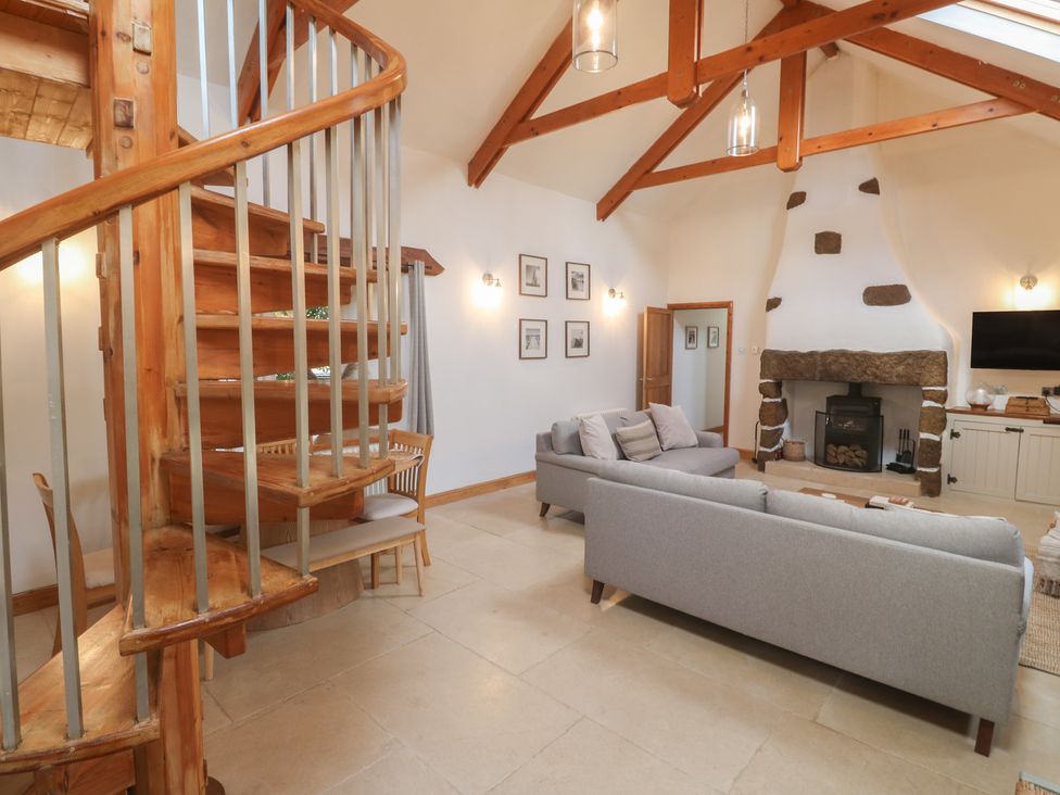 A living room with a spiral staircase and fireplace at Riverside Barn in Stithians