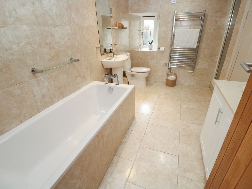 A bathroom with a bathtub, sink, toilet and towel rail at Riverside Barn Stithians