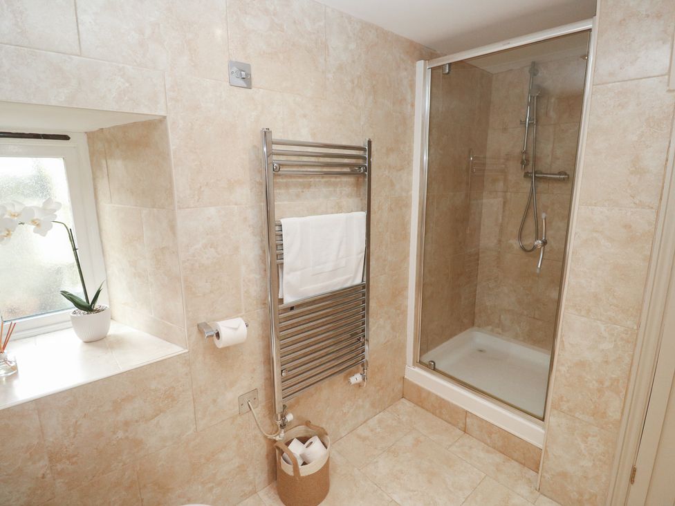 A bathroom with a shower and towel rail at Riverside Barn Stithians