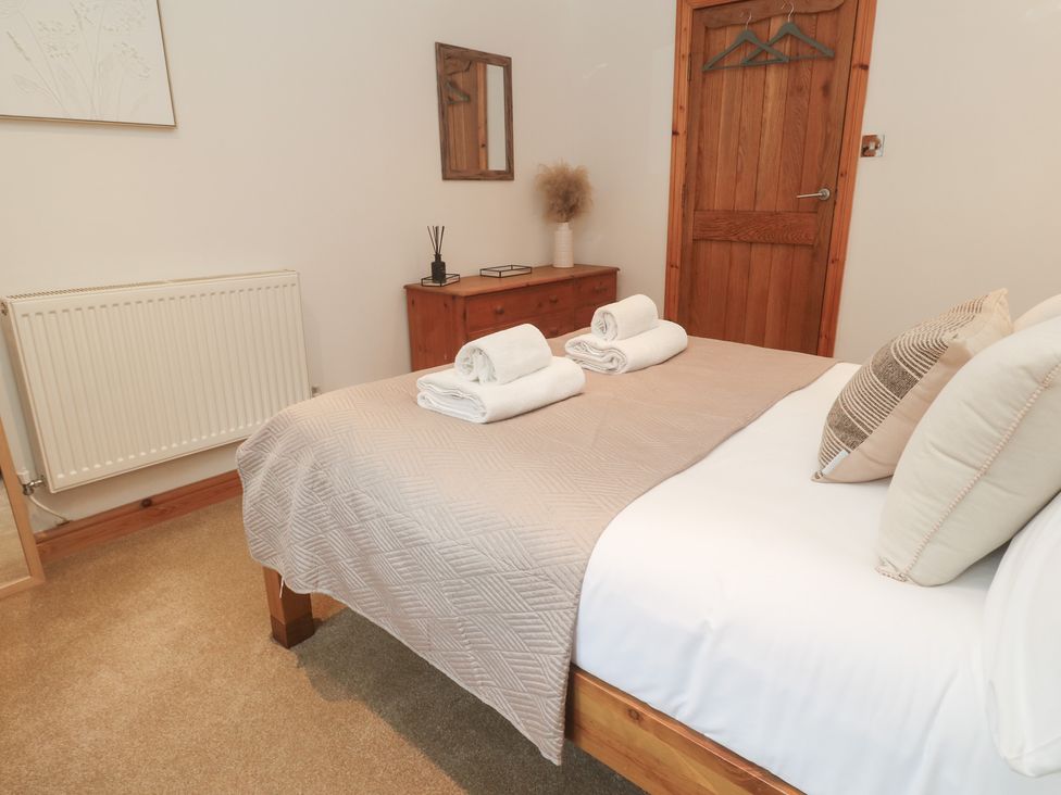 A bedroom with a bed and towels on top at Riverside Barn Stithians