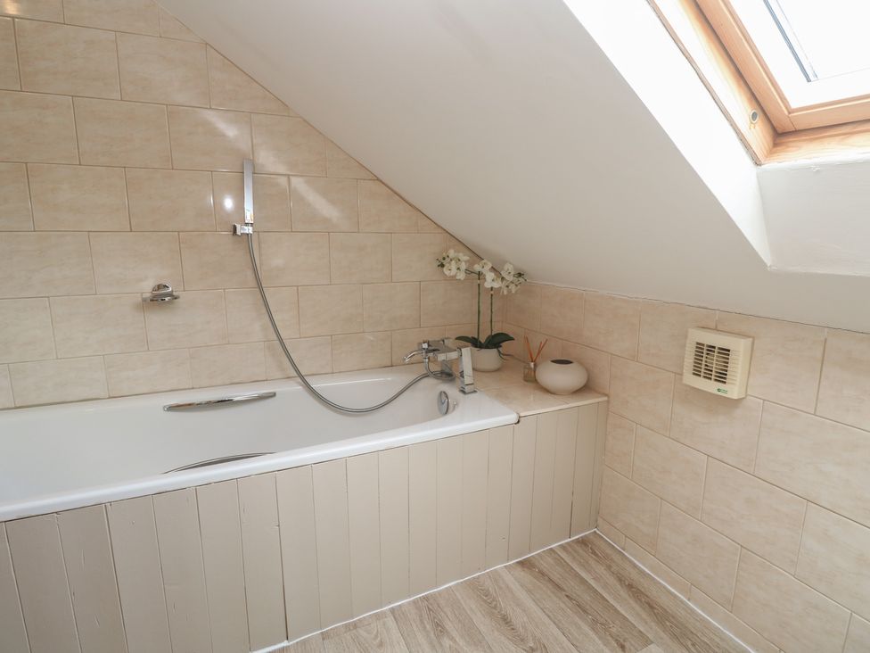 A bathroom with a bathtub and shower fixtures at Riverside Barn in Stithians