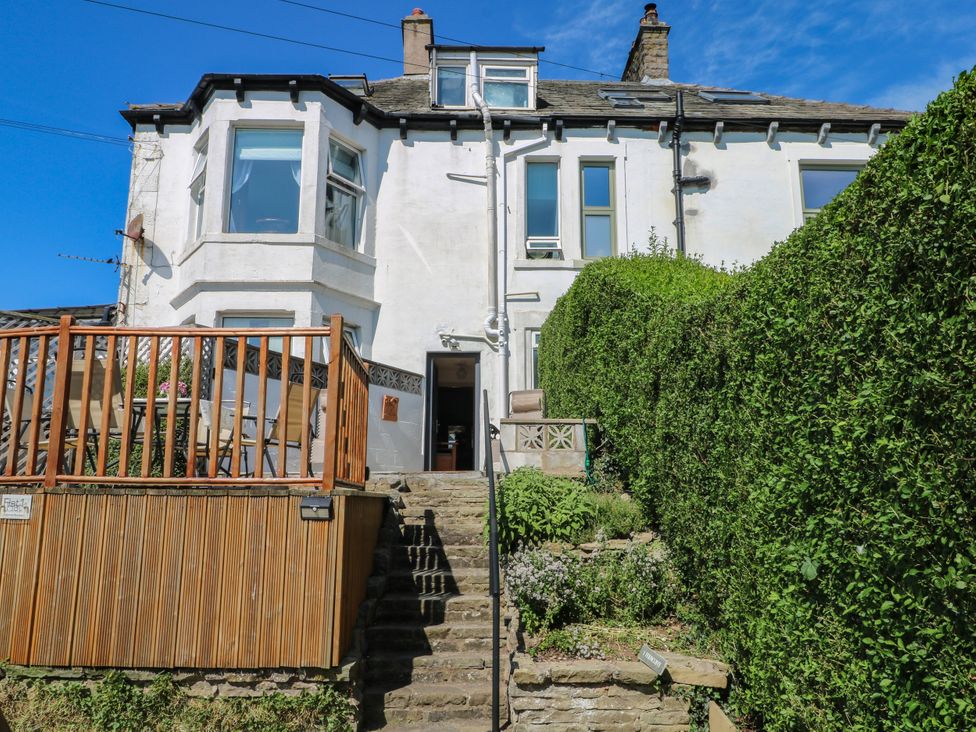 A house with a wooden deck and hedges at Ferncliffe