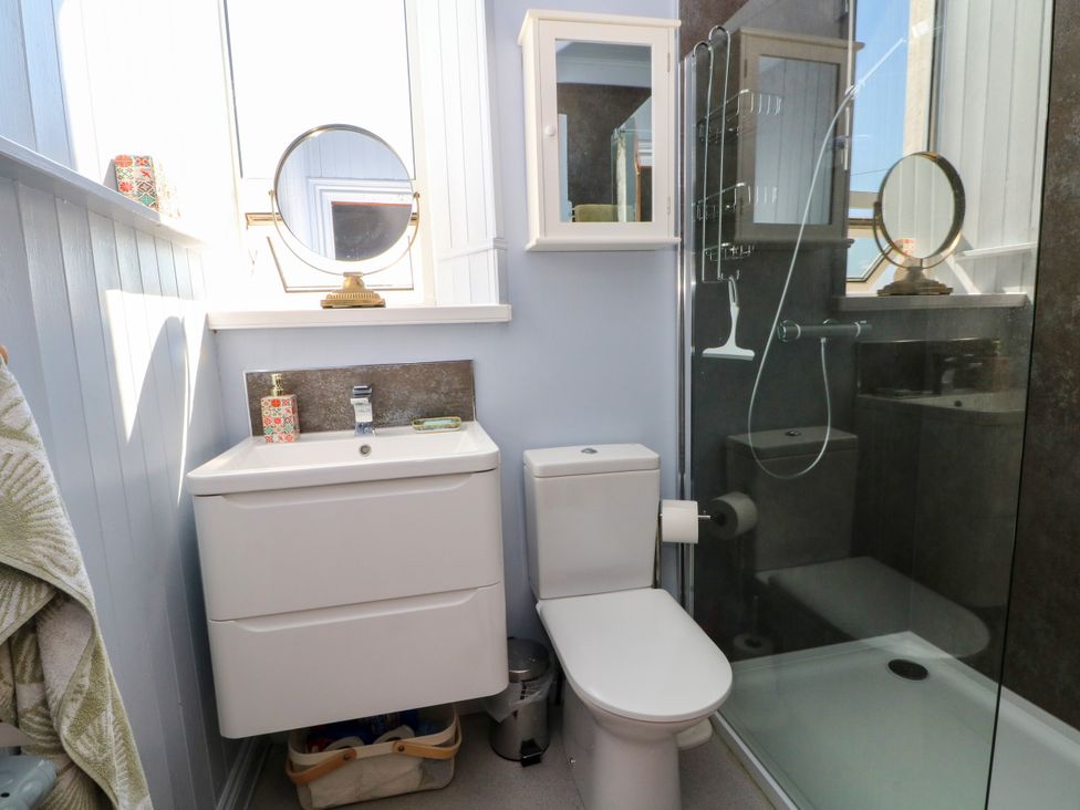 A bathroom with a sink, toilet, shower and mirror at Ferncliffe
