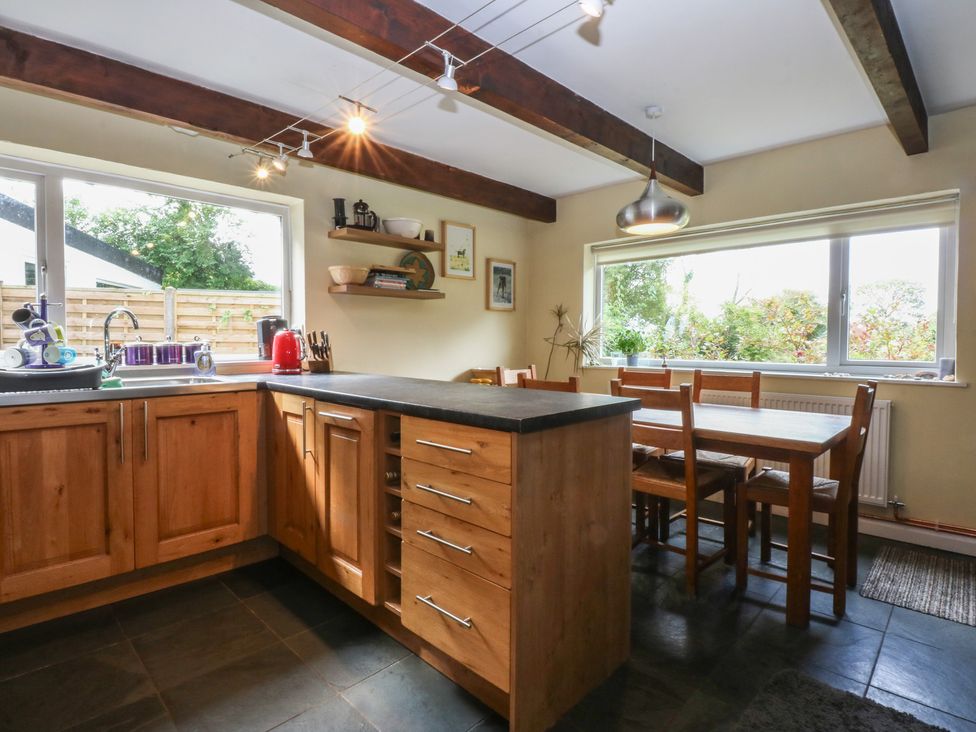 A kitchen with wooden cabinets and a dining table at Neuadd Wen in Gaerwen