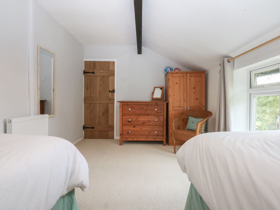 A bedroom with a bed, mirror, and dresser at Neuadd Wen in Gaerwen