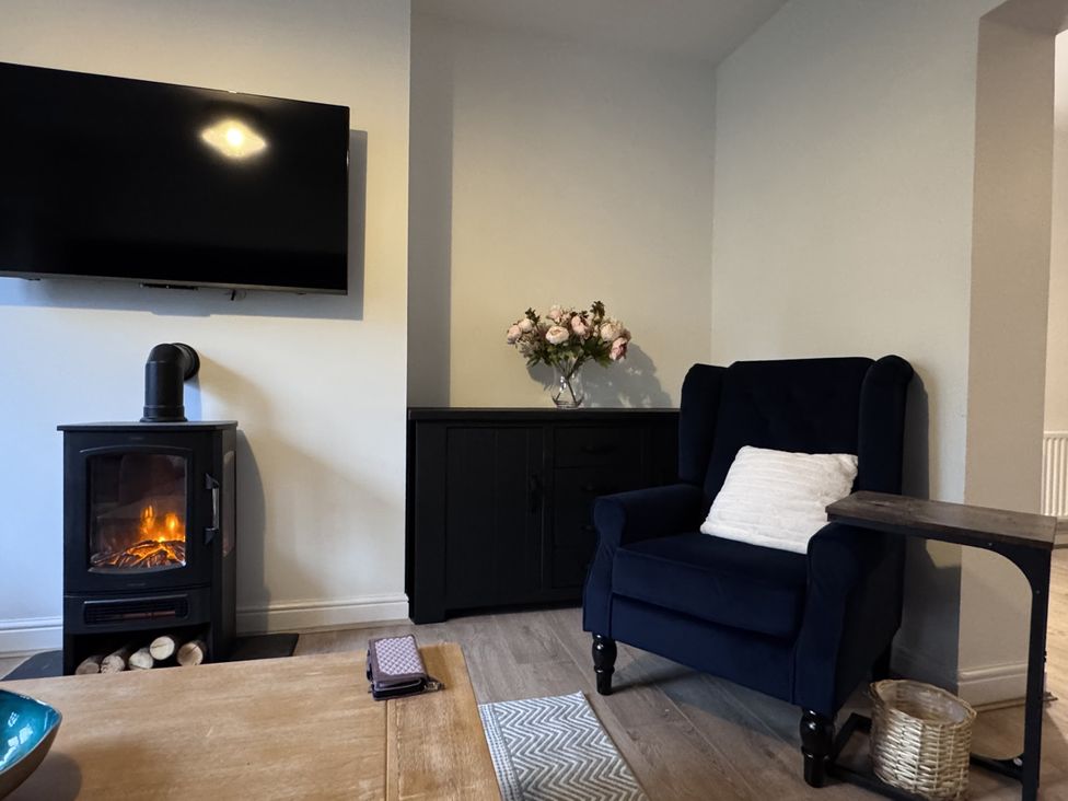 A living room with a television and a flower vase at Ironstone Cottage in Eston