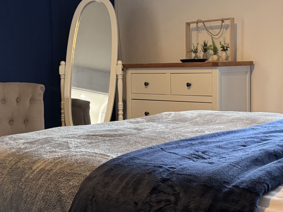 A bedroom with a bed and mirror at Ironstone Cottage Eston