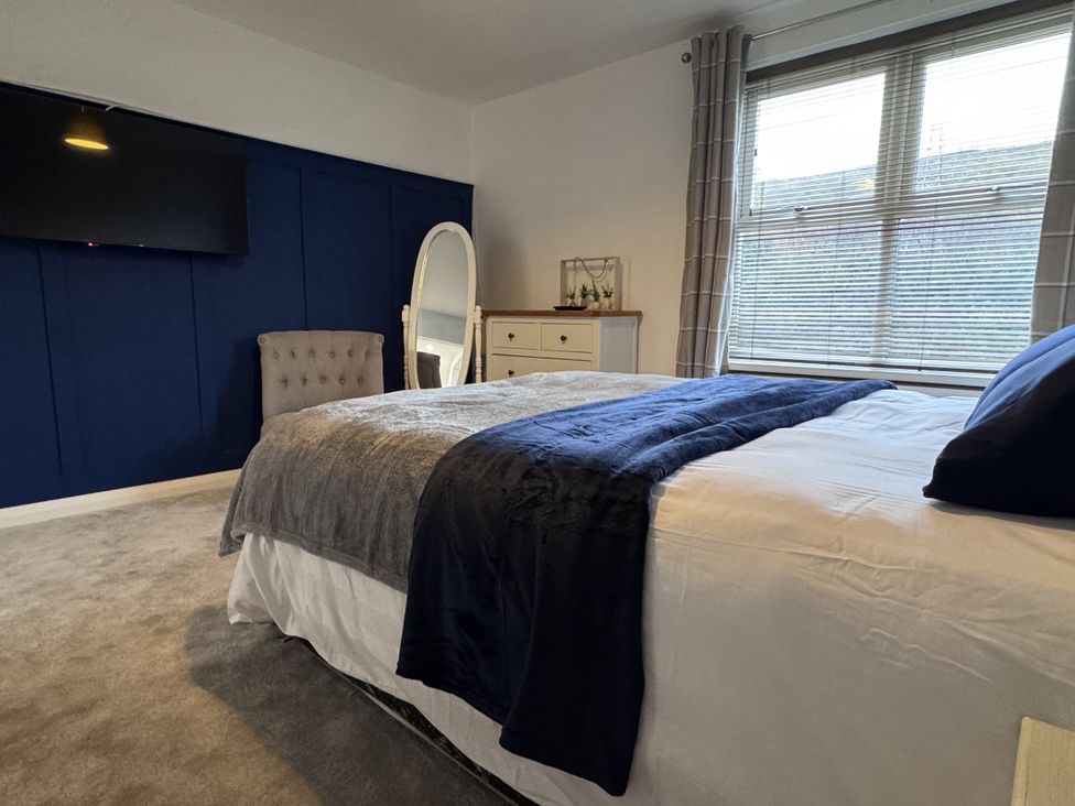 A bedroom featuring a bed, television, mirror, dresser and chair at Ironstone Cottage in Eston