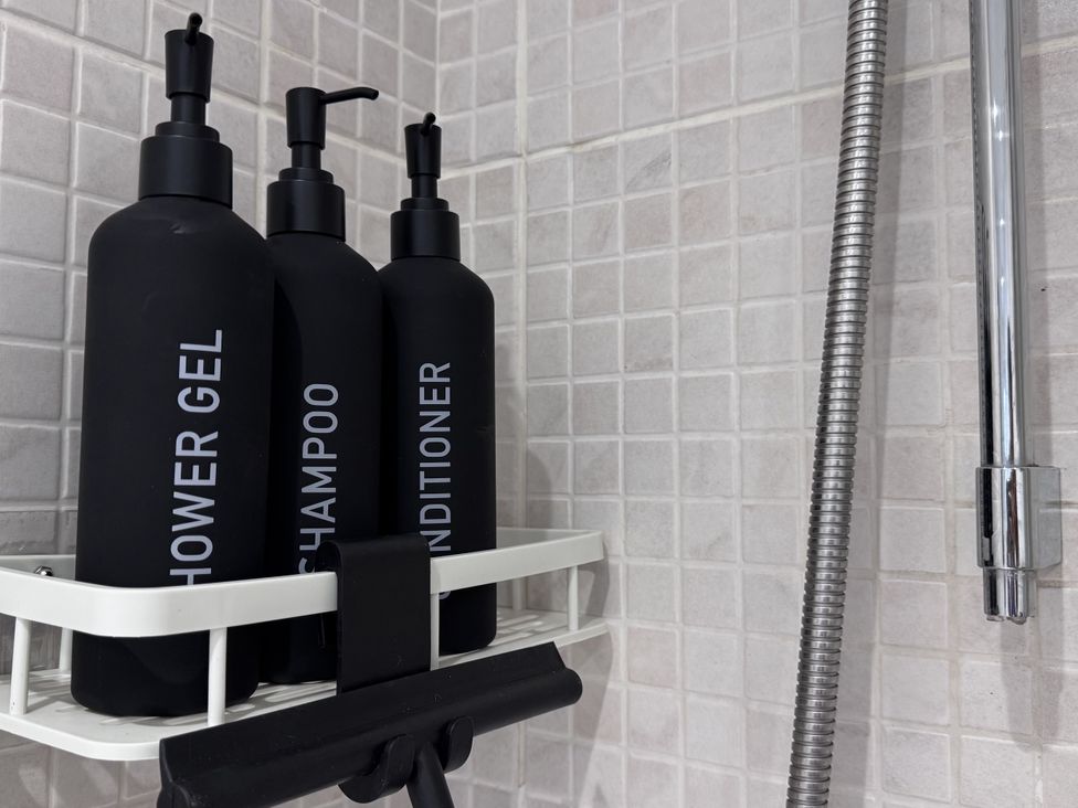 Bottles of shower gel shampoo and conditioner in a bathroom at Ironstone Cottage Eston