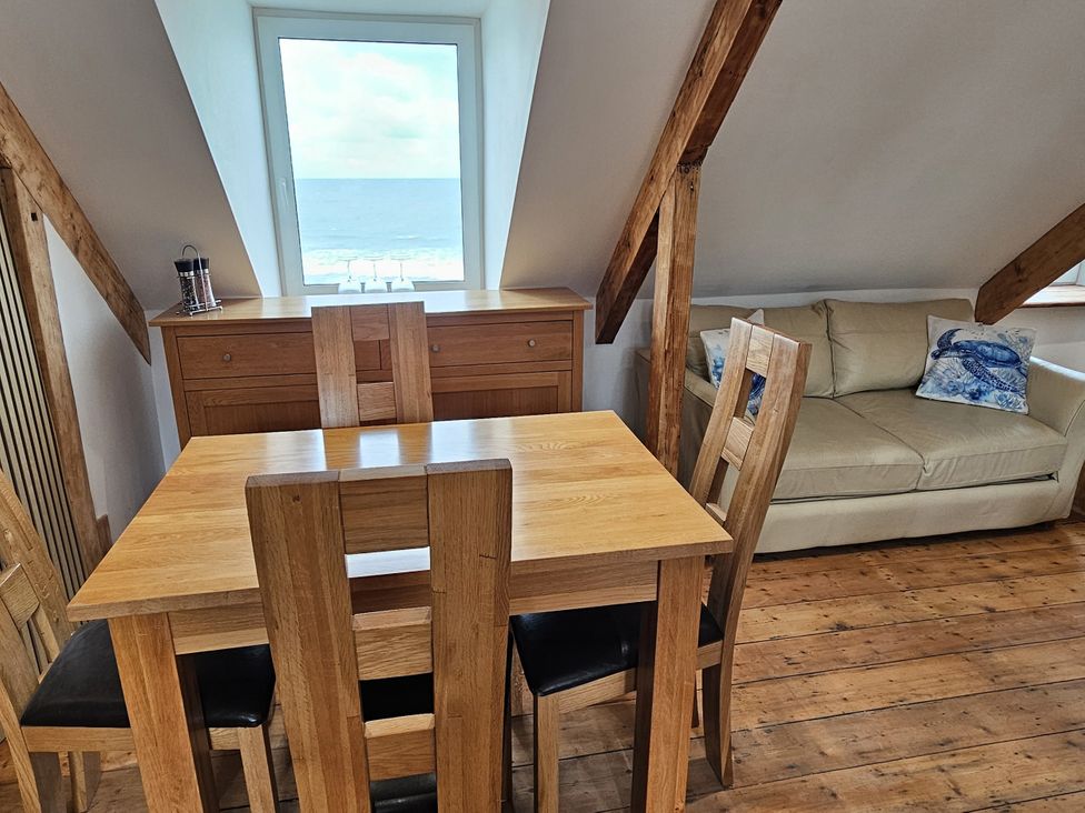 A dining area with a table and chairs and a view of the sea at Awel Deg in Cardigan