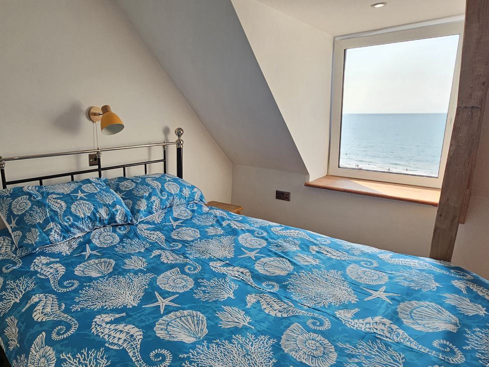 A bedroom with a bed and a window overlooking the sea at Awel Deg in Cardigan
