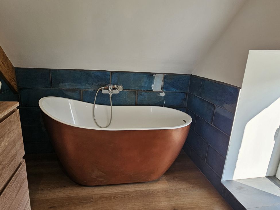 A bathroom with a freestanding bathtub and blue wall tiles at Awel Deg in Cardigan
