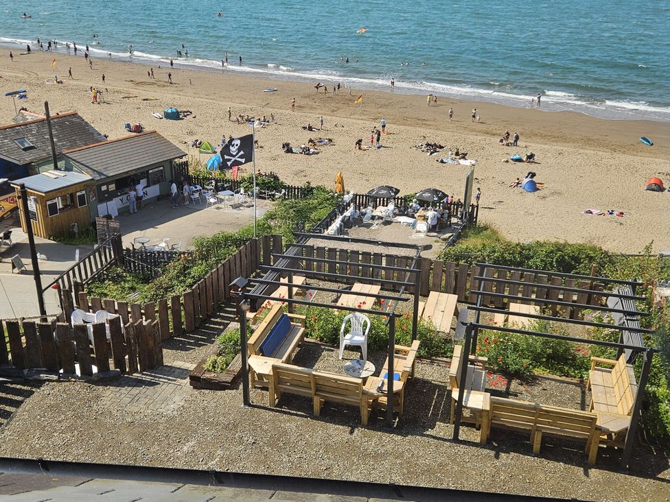 A beach scene with sun umbrellas and seating at Awel Deg in Cardigan