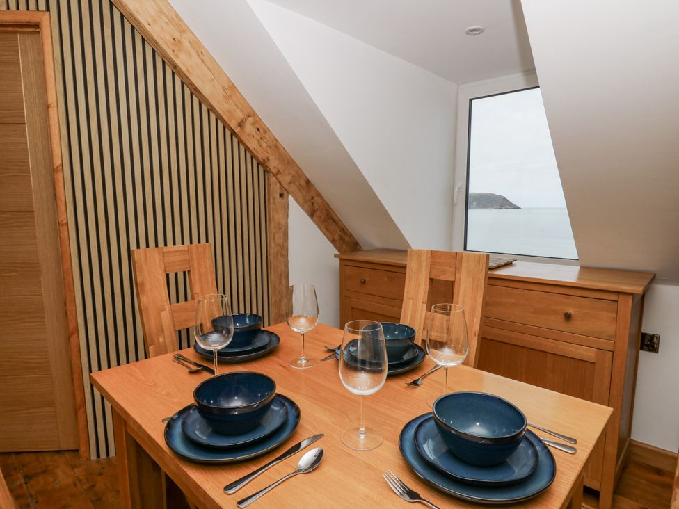 A dining room with a table set for meal at Awel Deg, Tresaith
