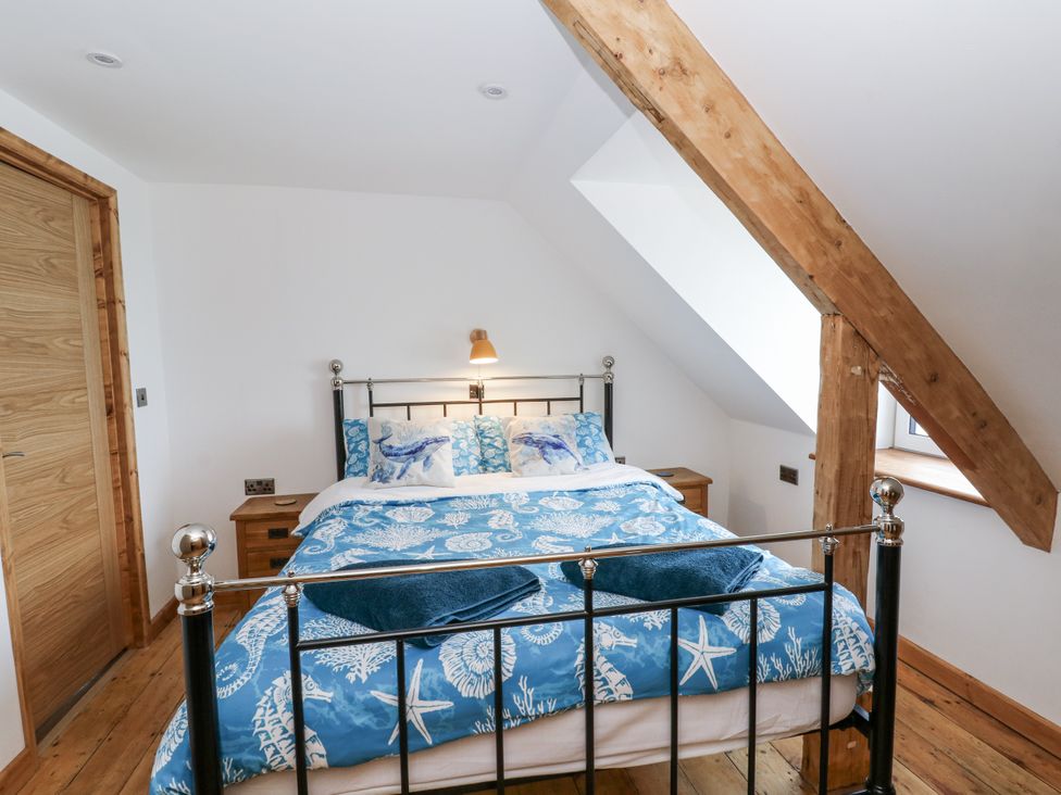 A bedroom with a bed and bedside tables at Awel Deg, Tresaith