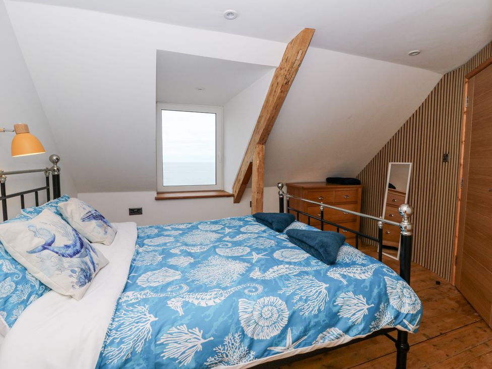 A bedroom with a bed and a window at Awel Deg, Tresaith
