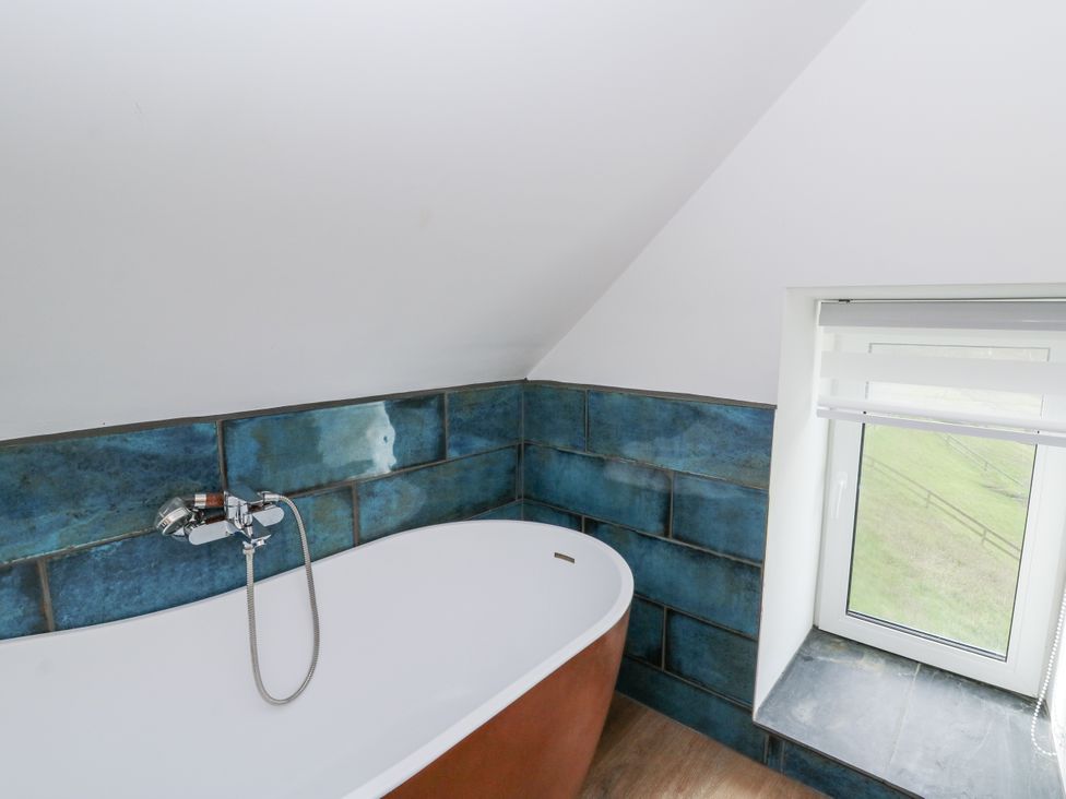 A bathroom with a bathtub and a window at Awel Deg, Tresaith