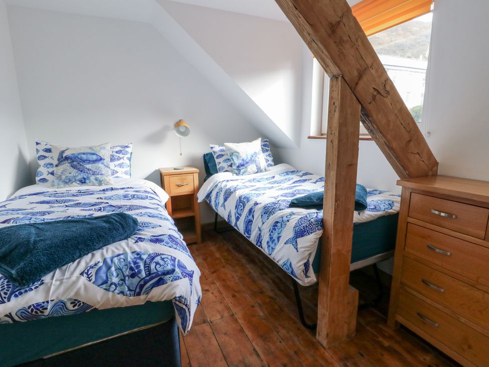 A bedroom with two beds and a nightstand at Awel Deg, Tresaith
