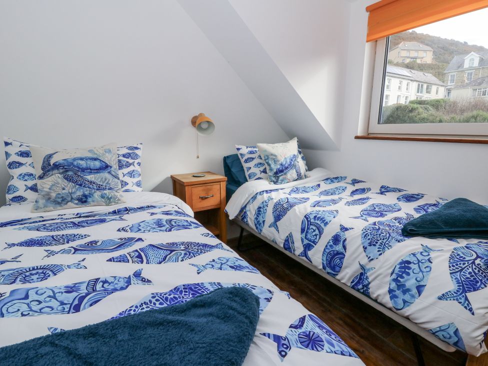 A bedroom with two beds and a window at Awel Deg, Tresaith