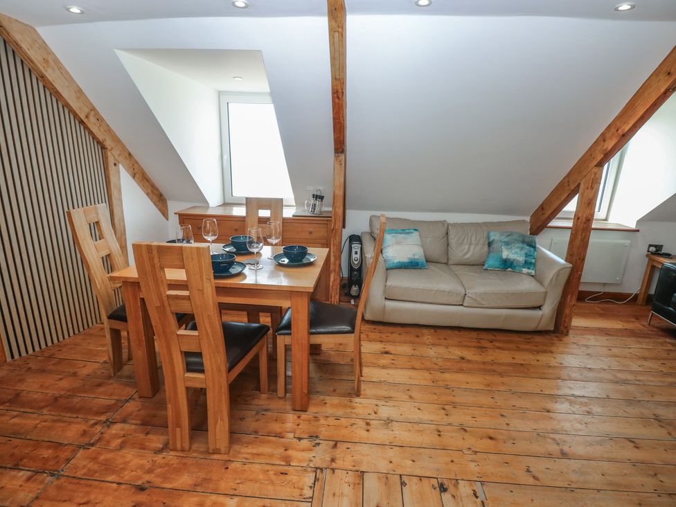 A living room with a dining table and sofa at Awel Deg, Tresaith