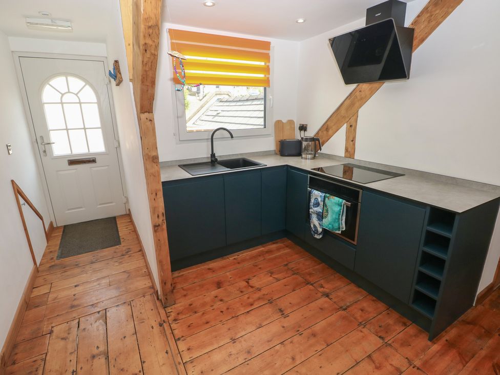 A kitchen with a sink, cooker, and front door at Awel Deg, Tresaith