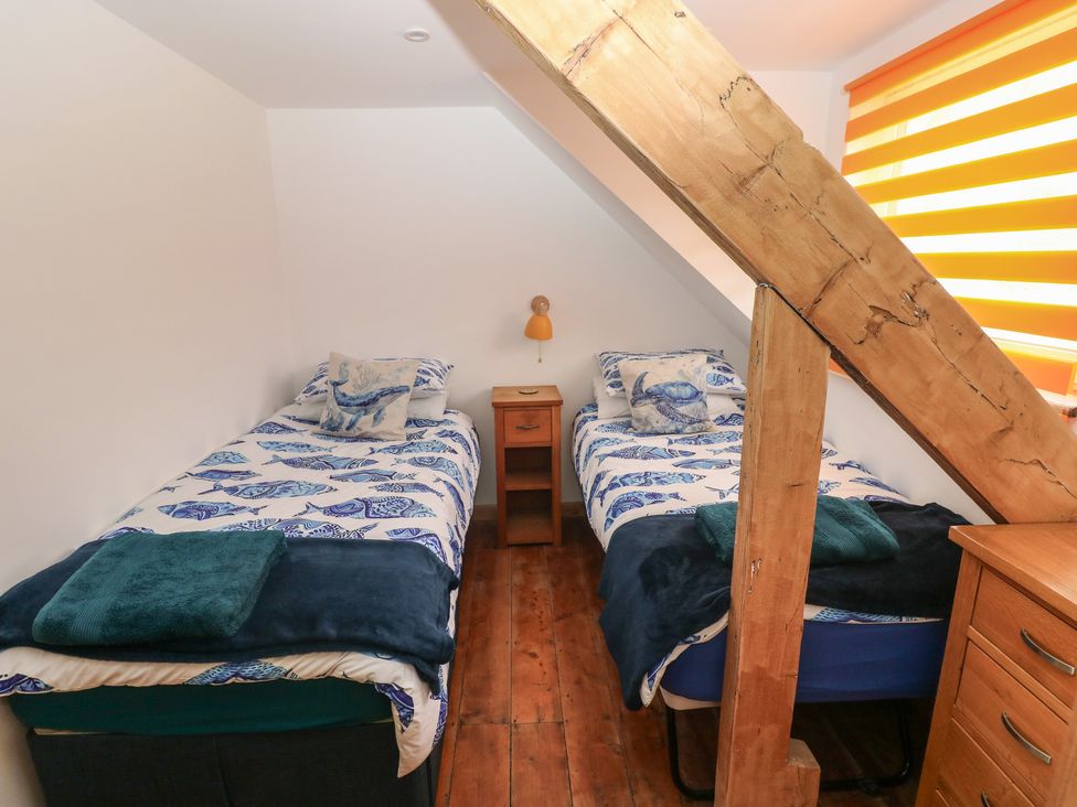 A bedroom with two single beds and a bedside table at Awel Deg, Tresaith