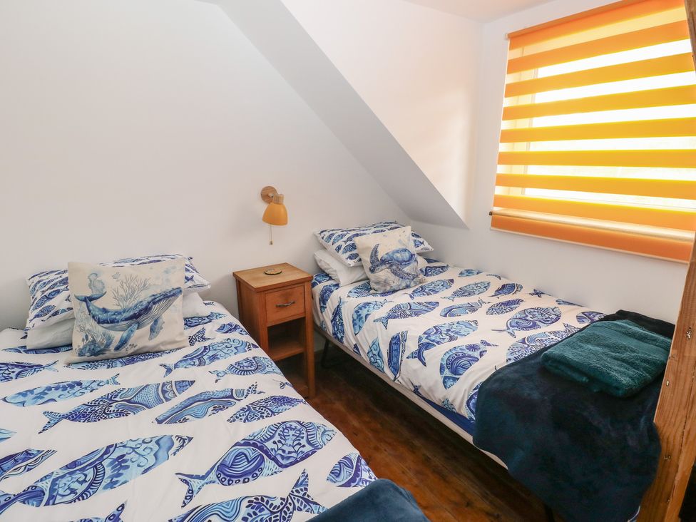 A bedroom with two beds and a nightstand at Awel Deg, Tresaith