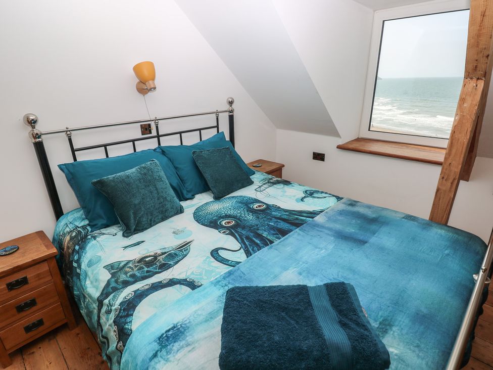 A bedroom with a bed and window at Awel Deg, Tresaith