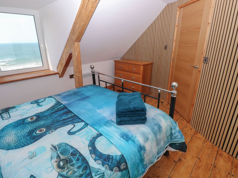 A bedroom with bed and dresser at Awel Deg, Tresaith