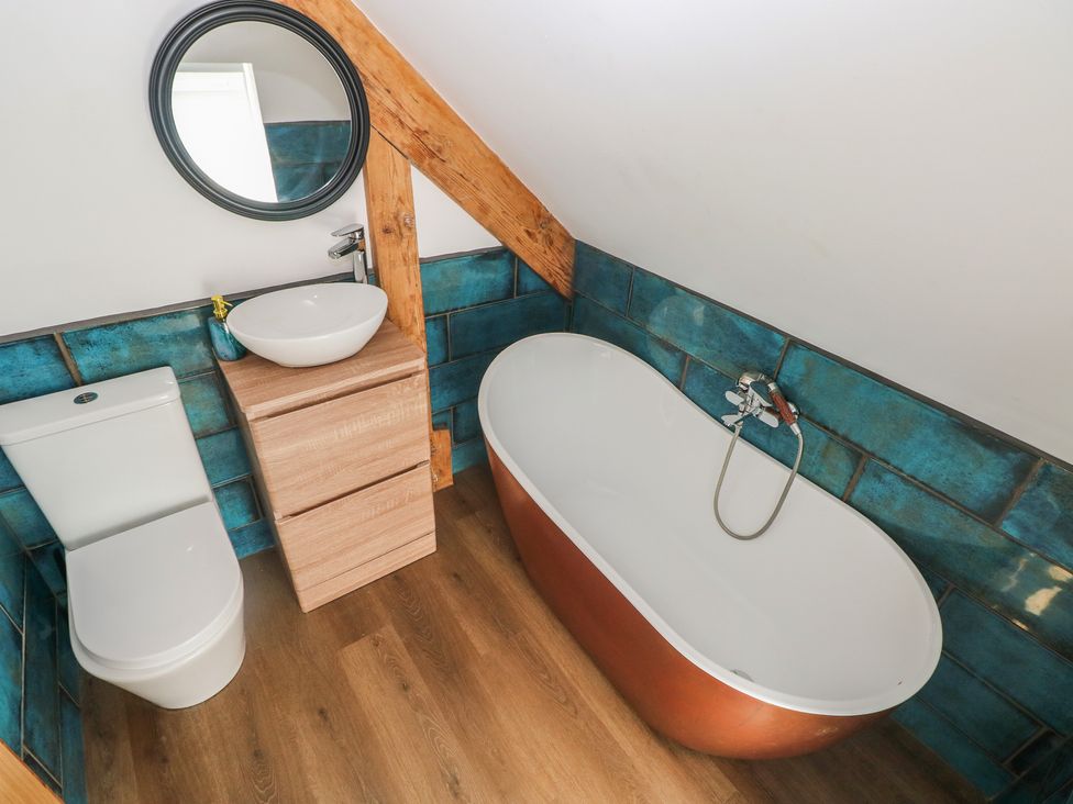 A bathroom with a bathtub, toilet, and sink at Awel Deg, Tresaith