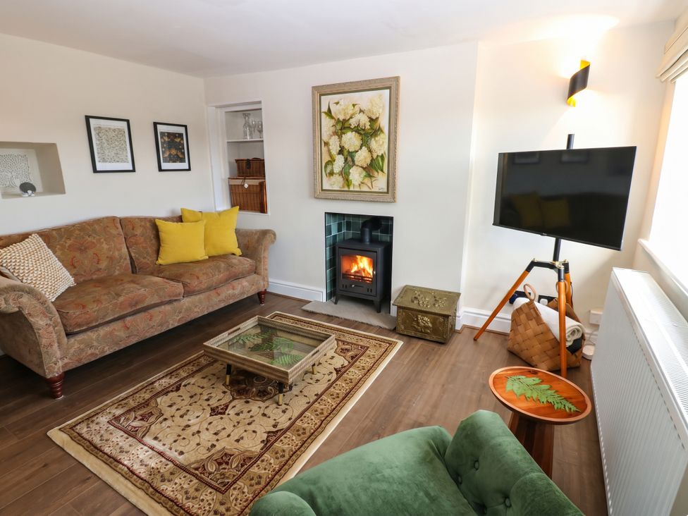 A living room with a sofa, fireplace, and television at Ashtree Cottage