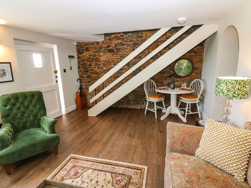 A living room with an armchair and dining table at Ashtree Cottage