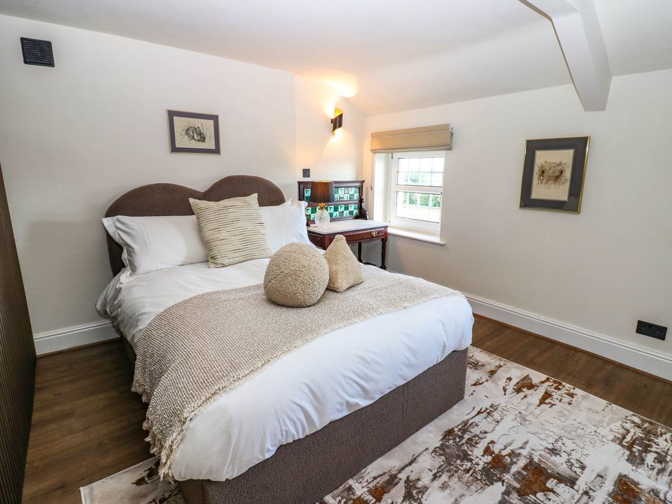A bedroom with a bed and a table at Ashtree Cottage
