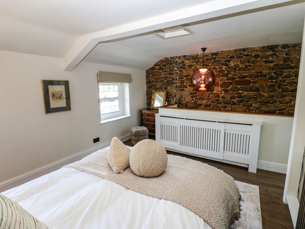 A bedroom with a bed and stone wall at Ashtree Cottage