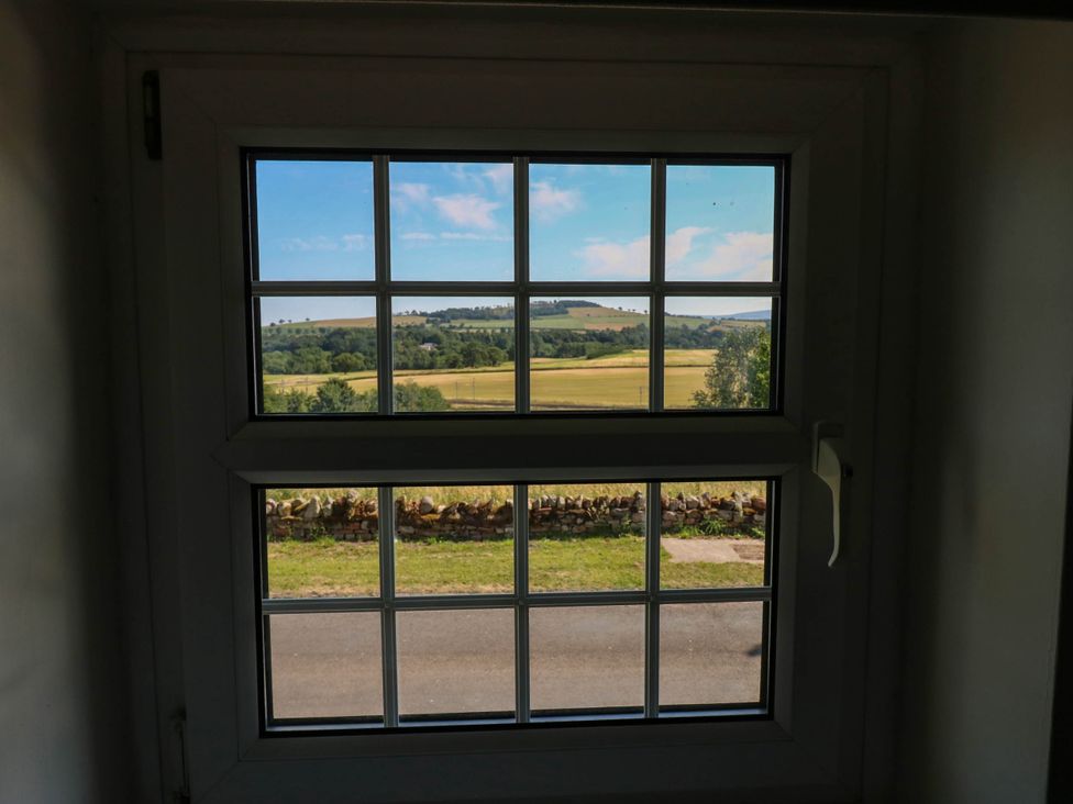 A view of fields and trees through a window at Ashtree Cottage