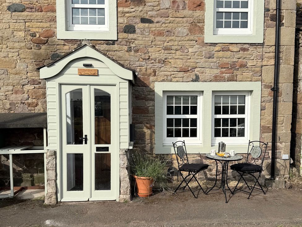 An outdoor seating area with a table and chairs at Ashtree Cottage in Mellguards near Armathwaite